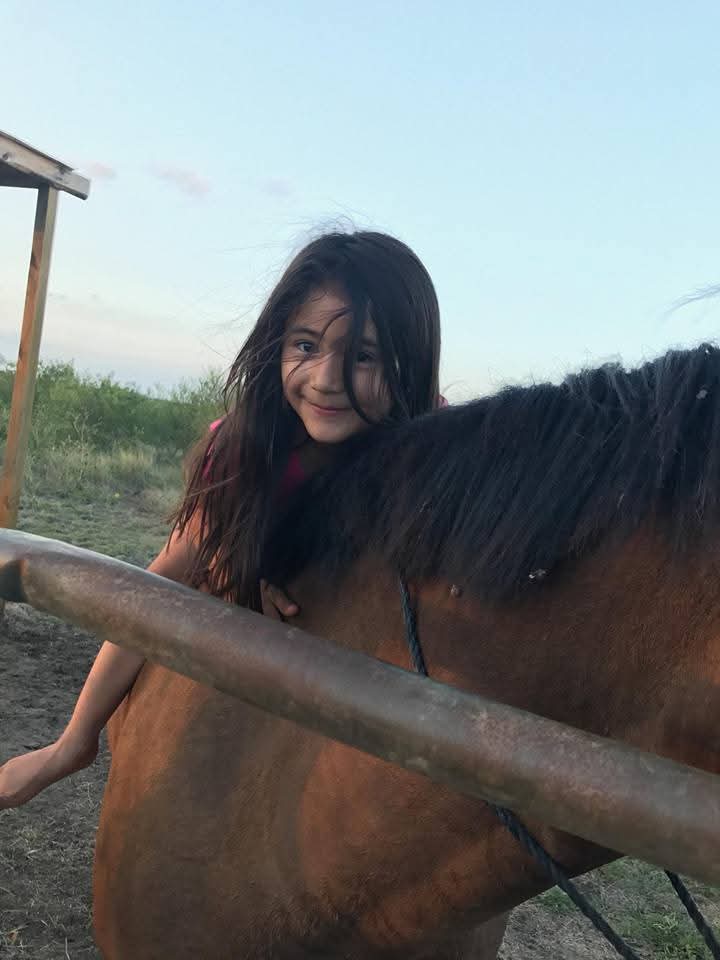 Alexa hugging a horse's neck at golden hour