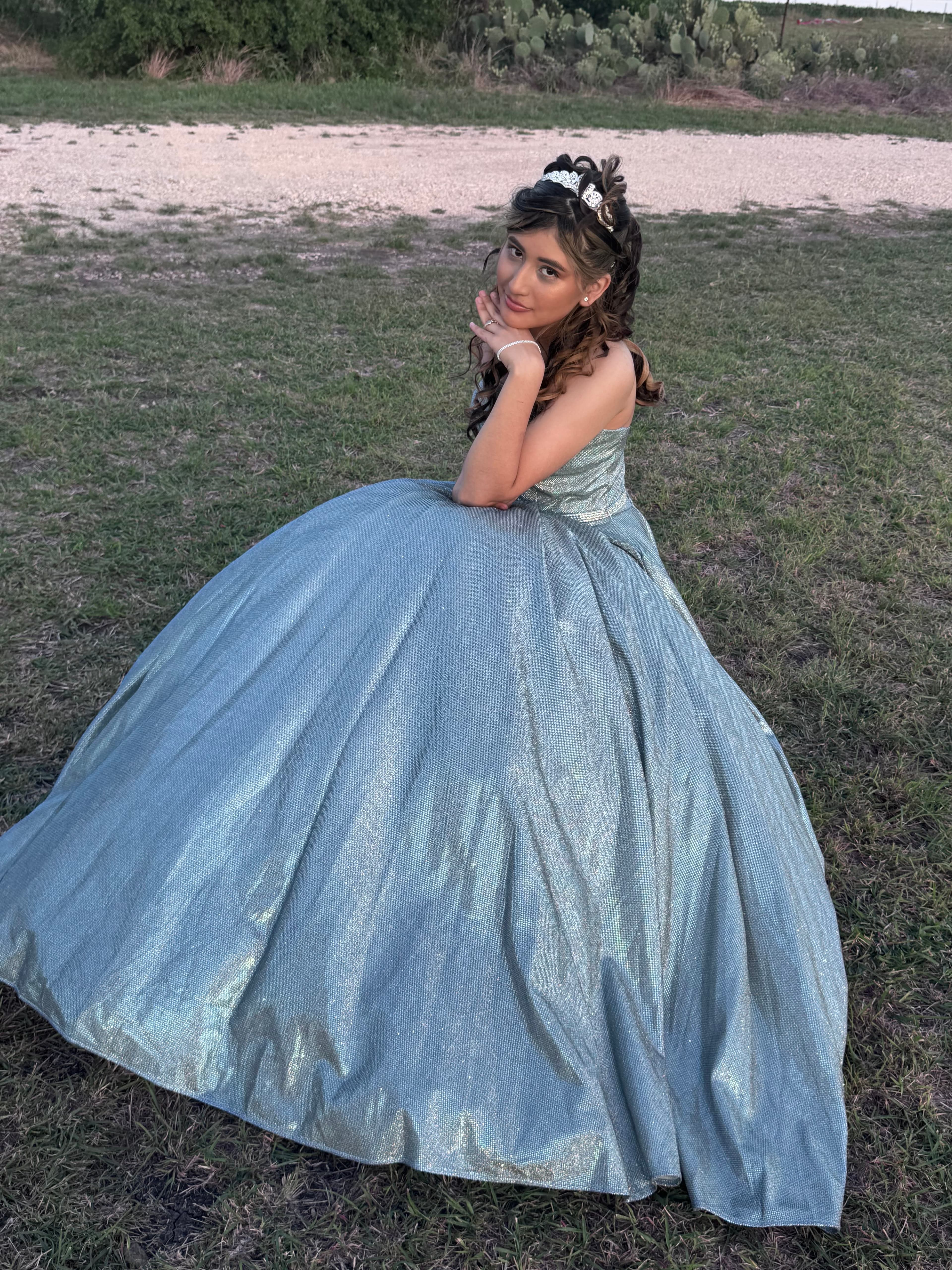 Alexa in her quinceañera gown, reclining in a grassy field at golden hour